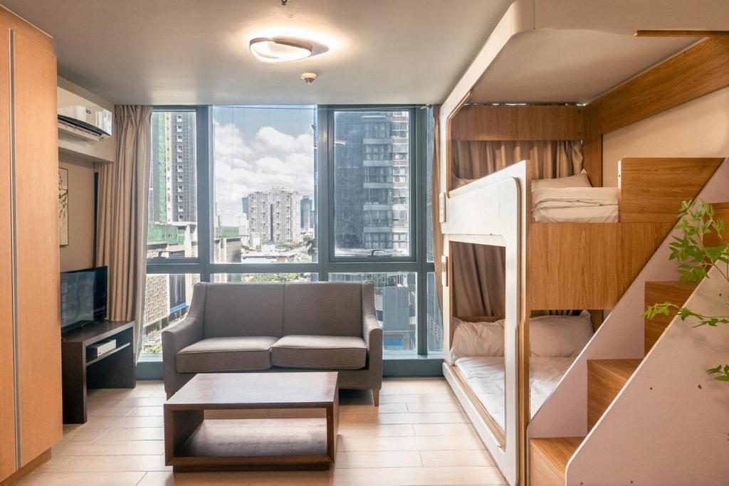 Habitación con cama, sofá y ventana en Uptown BGC Spacious Unit - 1 Queen bed and Bunkbed, en Manila