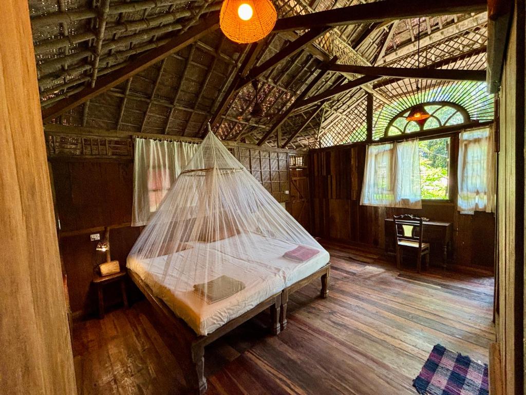 a bed in a room with a net in it at Bhakti Kutir in Palolem