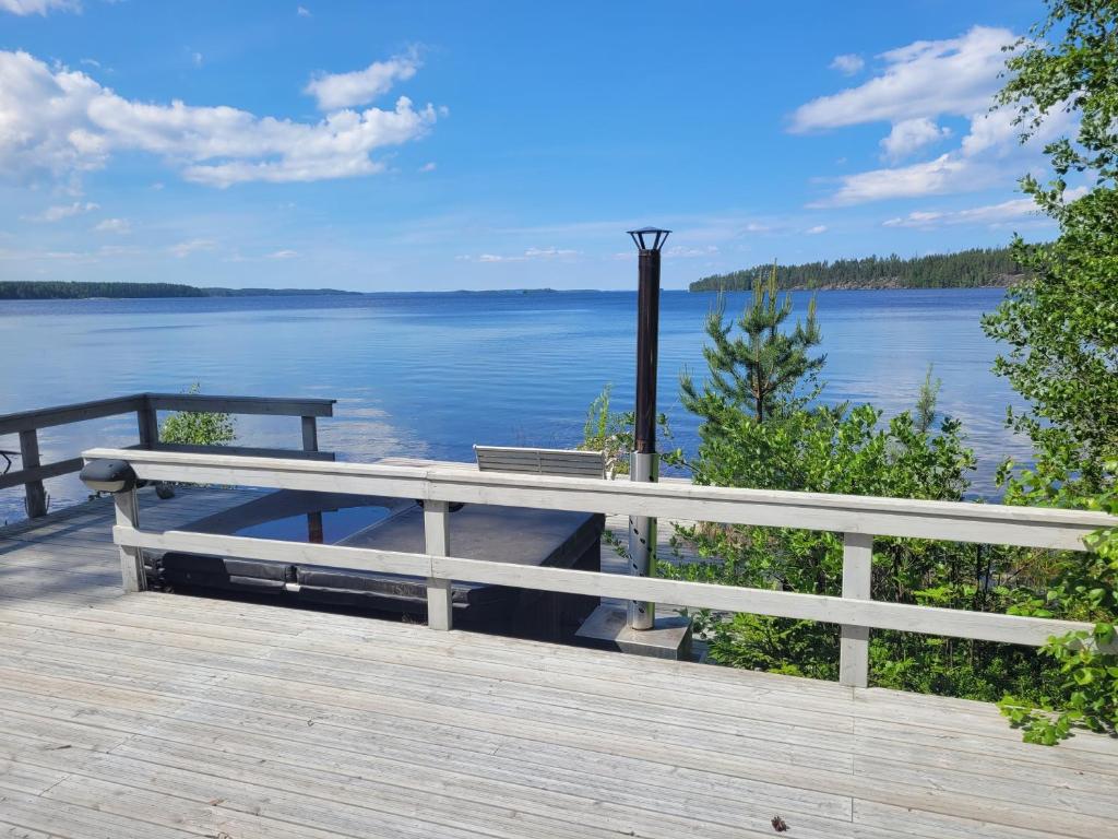 Un banco en un paseo marítimo con vista a un lago en Blue villa with private beach, en Kesälahti