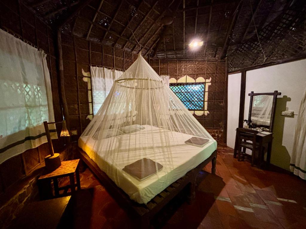a bed in a room with a net at Bhakti Kutir in Palolem