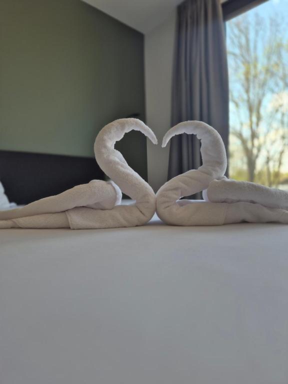 two towels in the shape of a heart on a bed at New Age Boardinghaus Bad Rappenau in Bad Rappenau