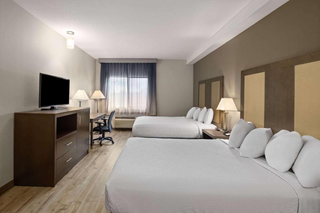 a hotel room with two beds and a flat screen tv at Baymont by Wyndham Moses Lake in Moses Lake