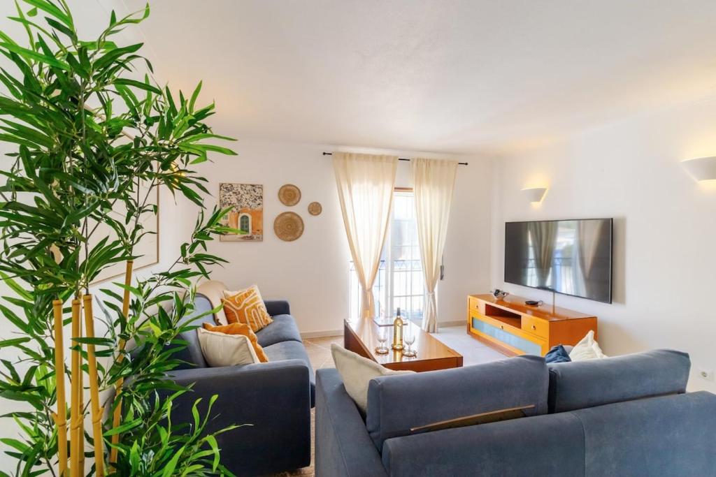 uma sala de estar com dois sofás azuis e uma televisão em Casa Maisie Apartment no Burgau