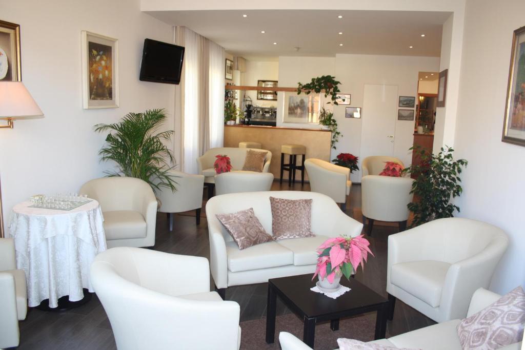 una sala d'attesa con sedie bianche e un tavolo di Hotel Sole Mare a Sanremo