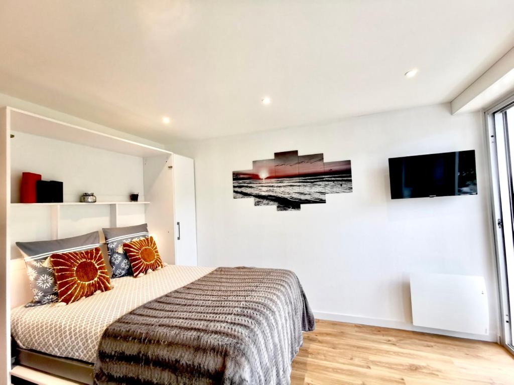 une chambre avec un lit et une télévision au mur dans l'établissement L'Azur - 50 m de la Plage, Wi-Fi, Moderne, Central, à La Baule