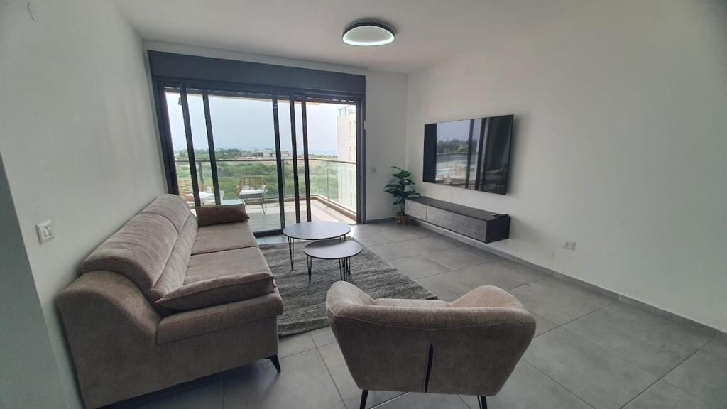 a living room with a couch and chairs and a tv at דירת נופש באכזיב על הים in Nahariyya