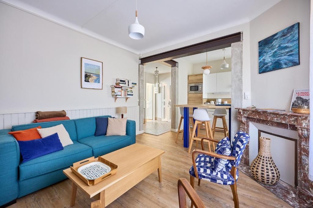 un salon avec un canapé bleu et une cheminée dans l'établissement Landemer - A 700 m de la plage, à Barneville-Carteret