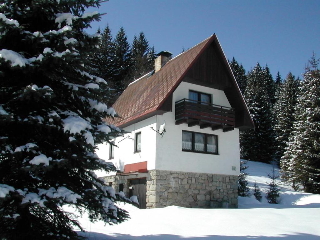 una casa con techo rojo en la nieve en Chalet Helena, en Nové Hamry