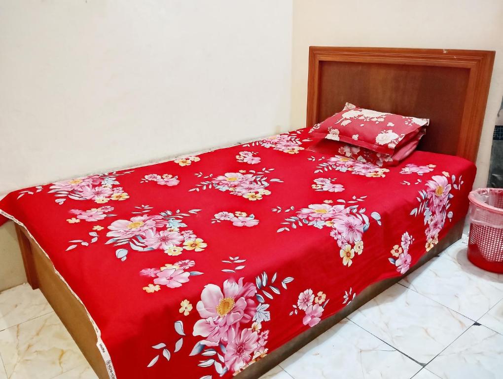 a bed with a red blanket with flowers on it at Hotel Garden View Jatrabari in Dhaka