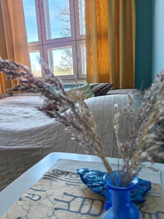 a blue vase on a table next to a bed at Kuohuvirran kartano in Nummistenkylä