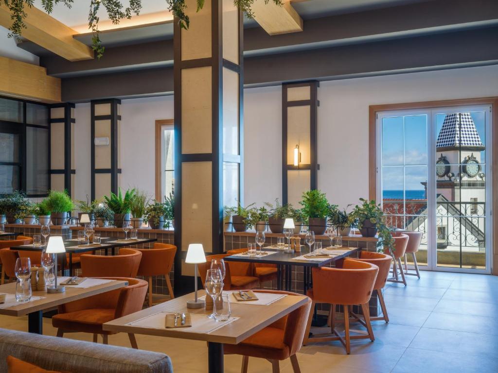 a restaurant with tables and chairs and a view of the ocean at Dreams Madeira Resort Spa & Marina in Caniçal