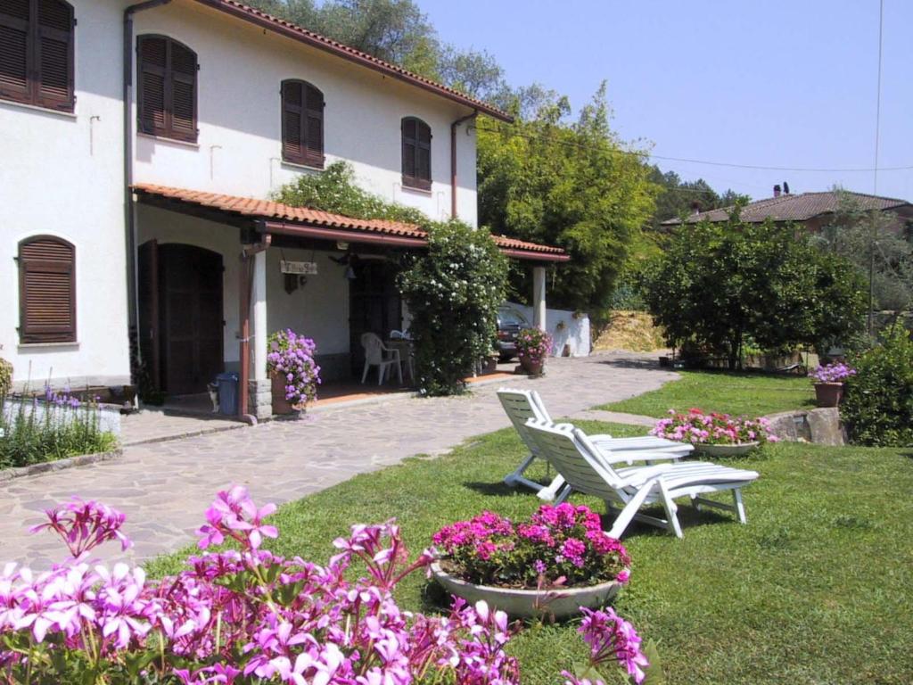 un giardino con due sedie bianche e fiori viola di Villino Isò a La Spezia