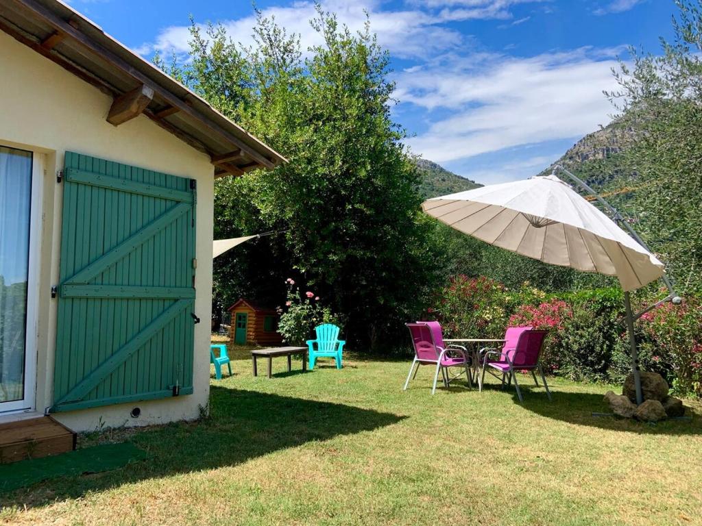 un patio avec une table, des chaises et un parasol dans l'établissement Maisonnette au calme avec jardin, à Saint-Jeannet