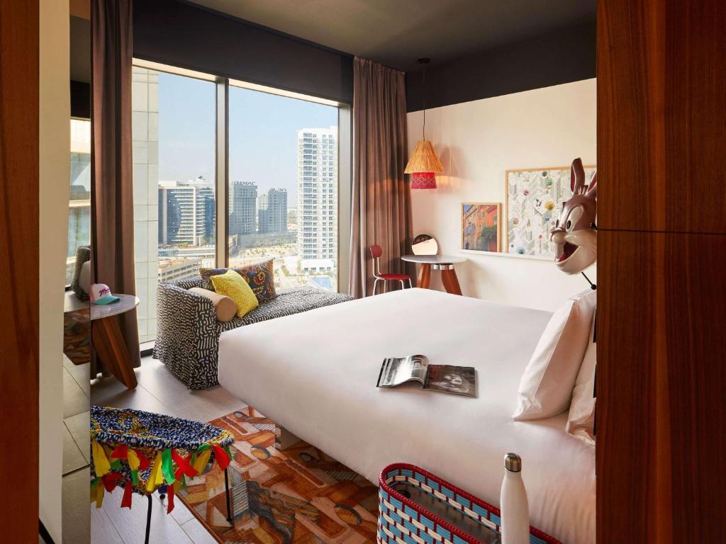 a hotel room with a large bed and a large window at Mama Shelter Dubai in Dubai