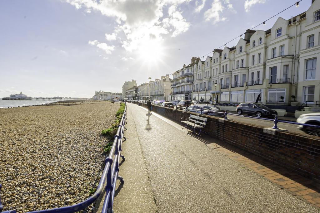 a row of buildings next to a beach with cars at The Majestic Hotel in Eastbourne