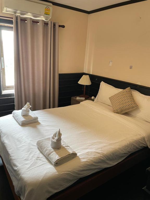 una camera da letto con un letto, asciugamani e una finestra di Panda Hostel 熊猫旅馆 a Vientiane
