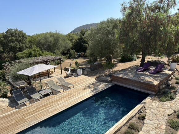 une piscine avec des chaises et une terrasse en bois dans l'établissement Villa avec piscine 14 personnes - Pinarello, à La Celle-sous-Gouzon