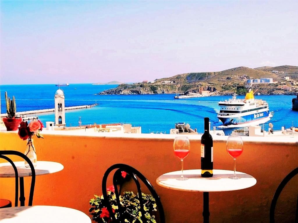 a restaurant with a balcony overlooking the ocean at Pefkakia Park in Ermoupoli