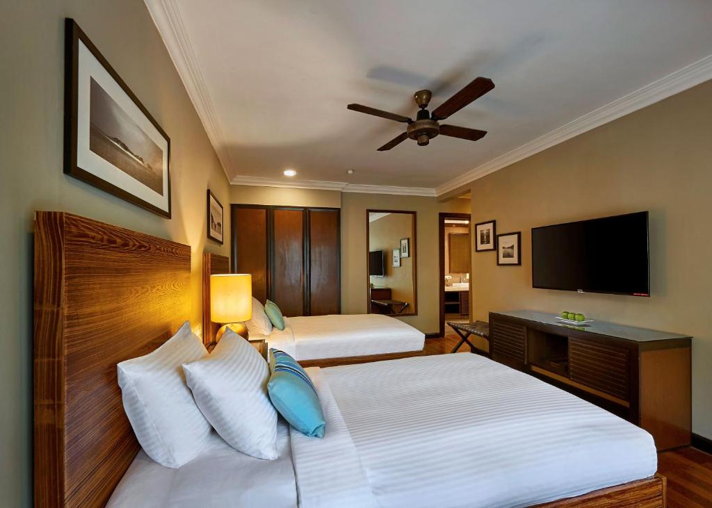 a bedroom with two beds and a flat screen tv at The Taaras Beach & Spa Resort in Redang Island