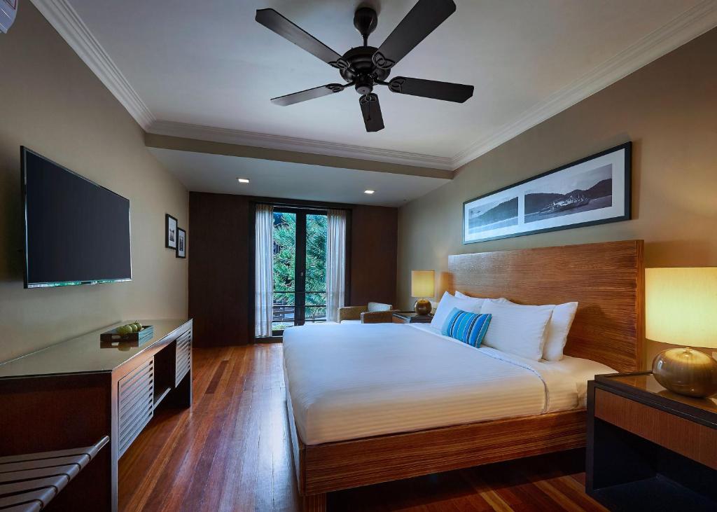 a bedroom with a large bed with a ceiling fan at The Taaras Beach & Spa Resort in Redang Island