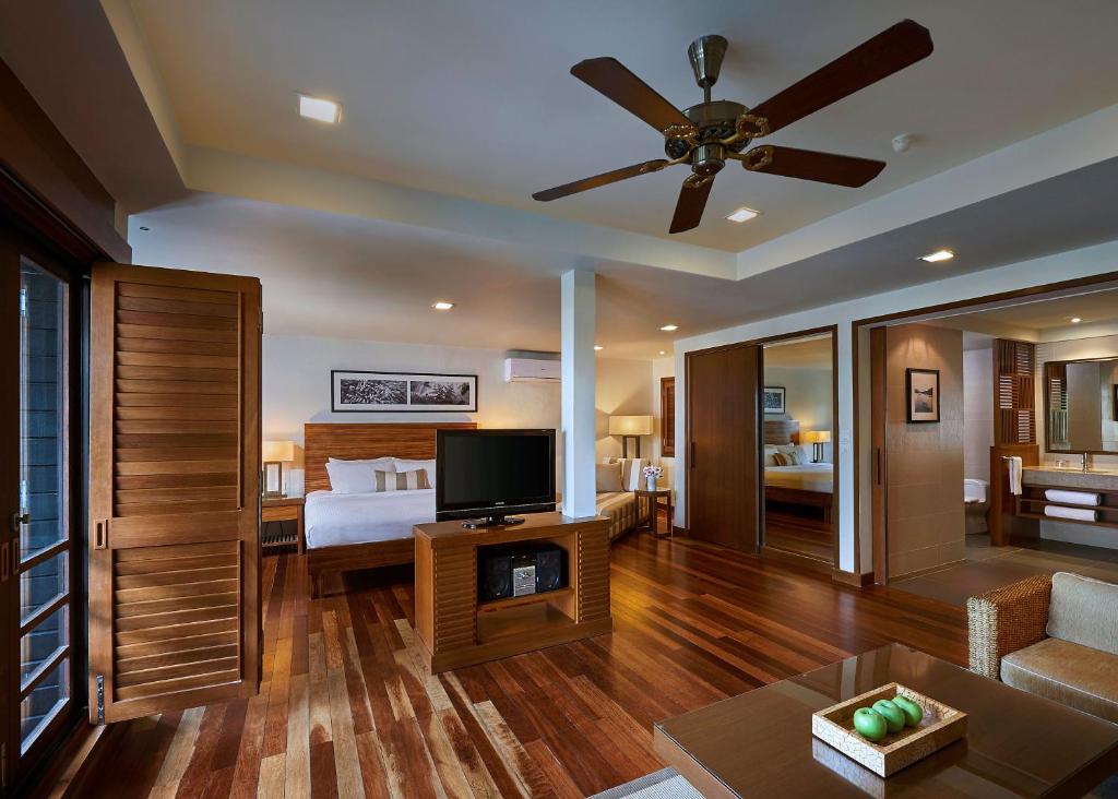 a living room with a bed and a ceiling fan at The Taaras Beach & Spa Resort in Redang Island
