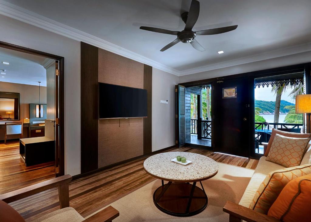a living room with a ceiling fan and a table at The Taaras Beach & Spa Resort in Redang Island