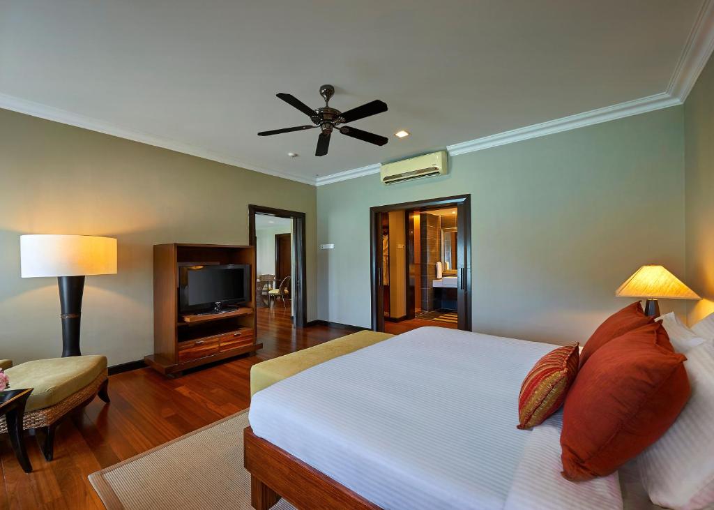 a bedroom with a white bed and a television at The Taaras Beach & Spa Resort in Redang Island