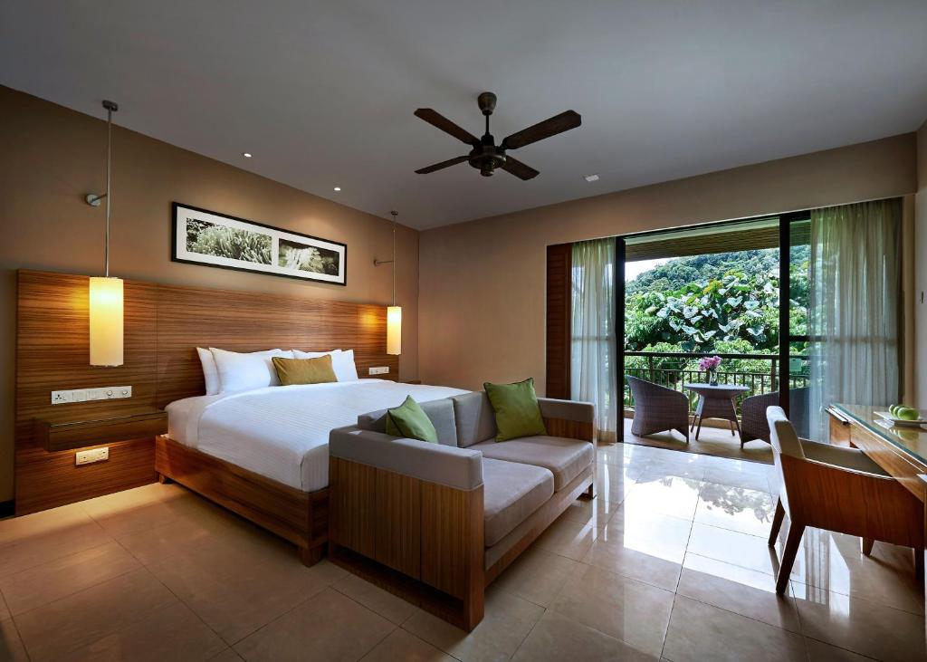 a bedroom with a bed and a couch and a window at The Taaras Beach & Spa Resort in Redang Island