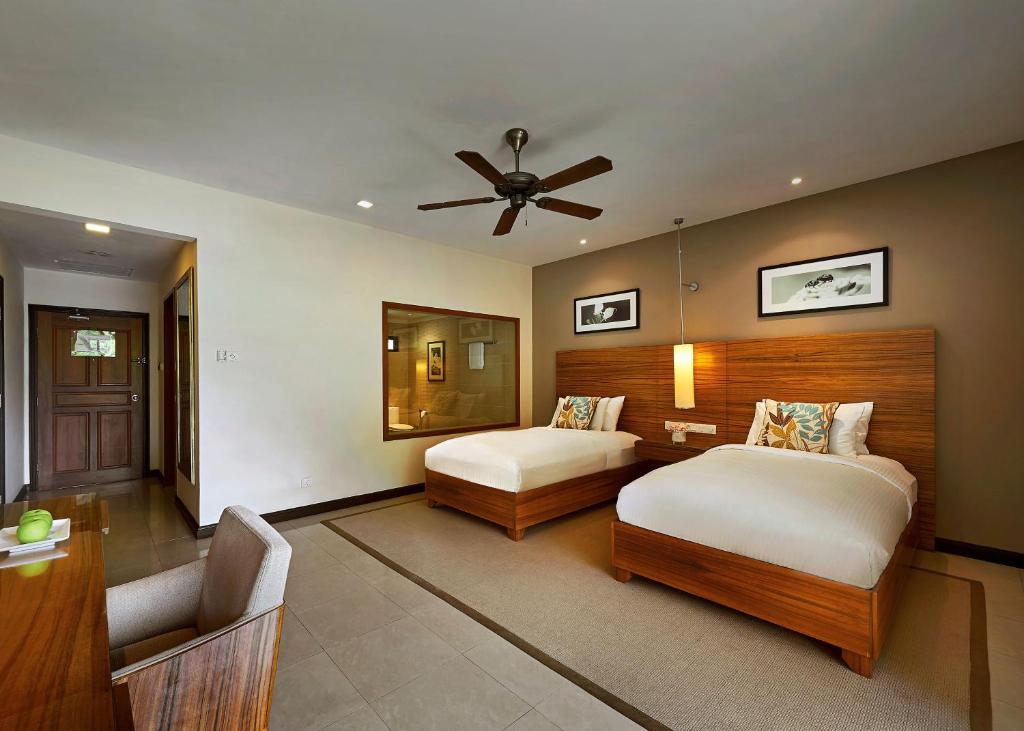 a bedroom with two beds and a ceiling fan at The Taaras Beach & Spa Resort in Redang Island