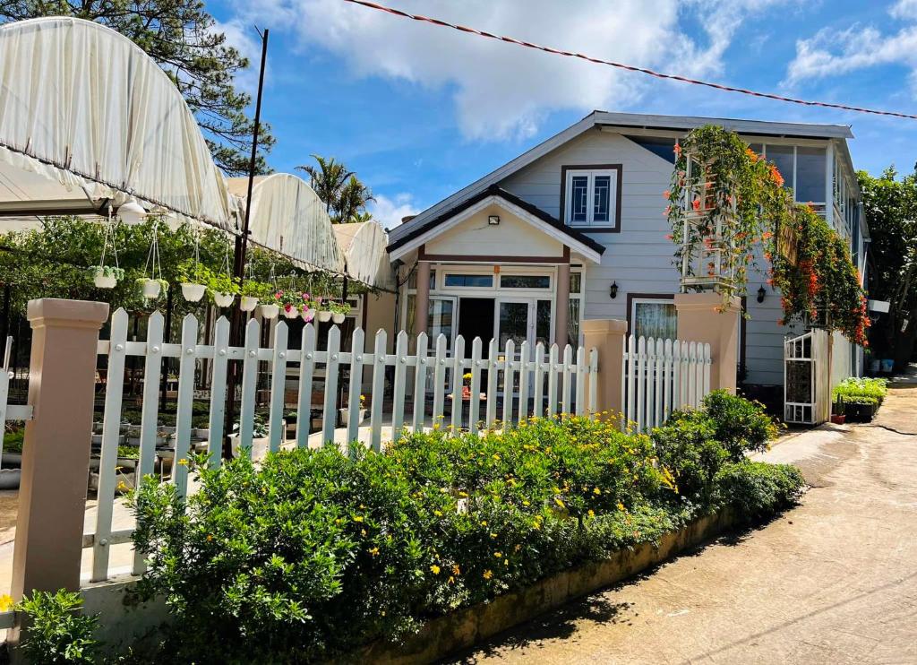 ein weißer Gartenzaun vor einem Haus in der Unterkunft Vườn Nhà Đan Homestay in Da Lat