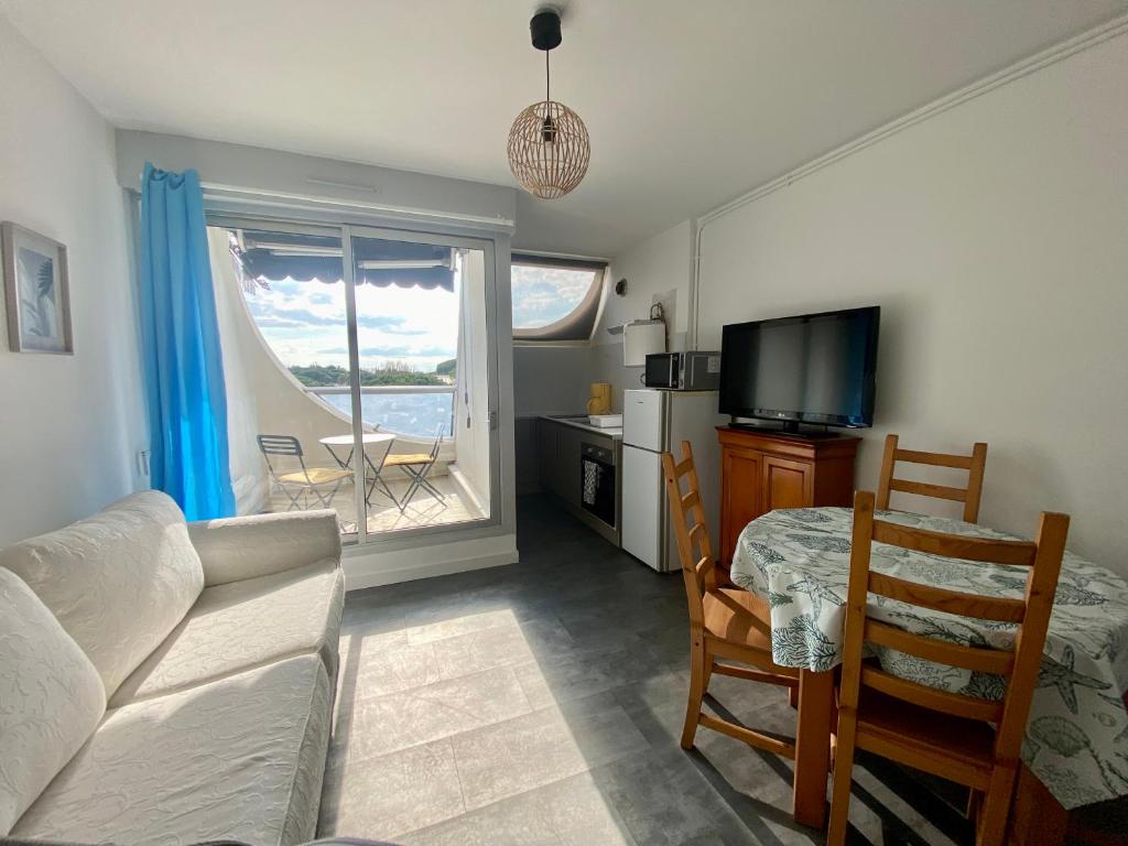 un salon avec un canapé et une table et une cuisine dans l'établissement Évasion paisible au Ponant, entre pins & étang , plage a pied, à La Grande Motte