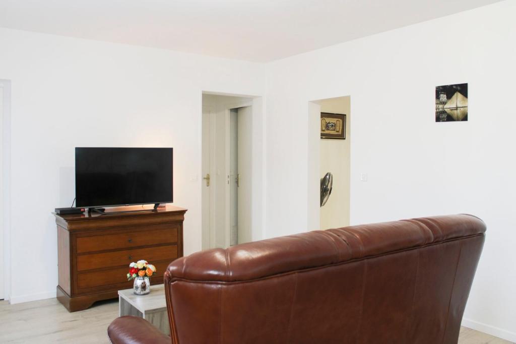 a living room with a couch and a flat screen tv at Renovated 2-bedroom apartment in Drancy