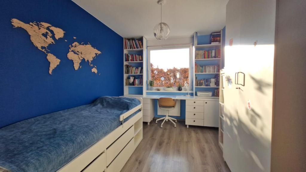 a bedroom with a blue wall with a bed and a desk at Osiedle Morskie in Pogórze