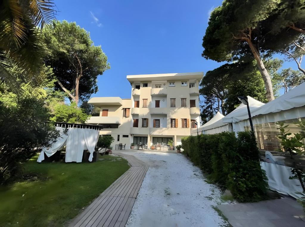 Un gran edificio blanco con árboles delante. en La Tavernetta dei Ronchi, en Marina di Massa