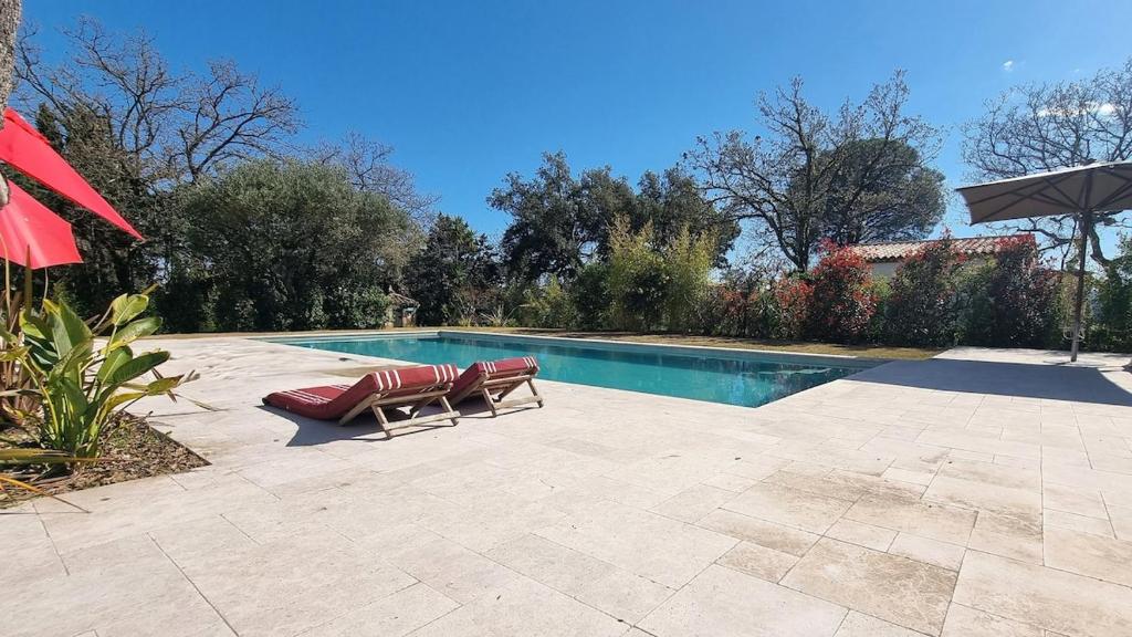 Una piscina con dos tumbonas al lado. en Villa Antassi enjoy the sun, en Grimaud