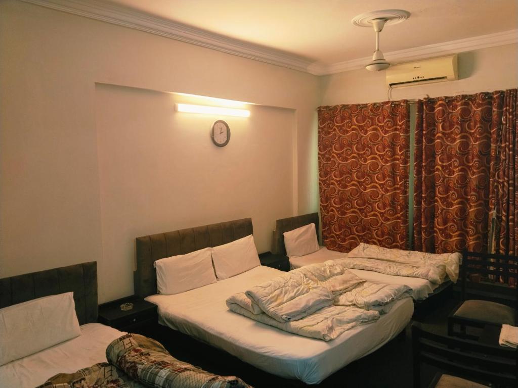 two twin beds in a room with a clock on the wall at Grand Arham Hotel in Dargai