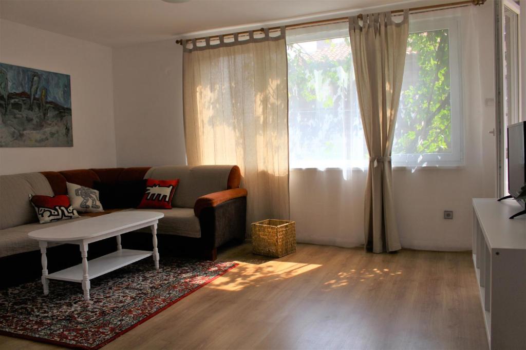 a living room with a couch and a table and a window at Апартаменти Амфора in Pomorie
