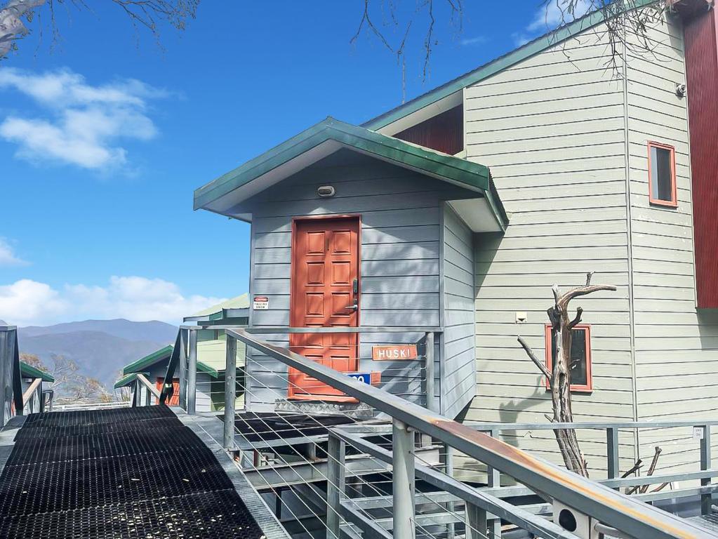 a small house with a red door on a building at Huski Ski Club in Mount Buller