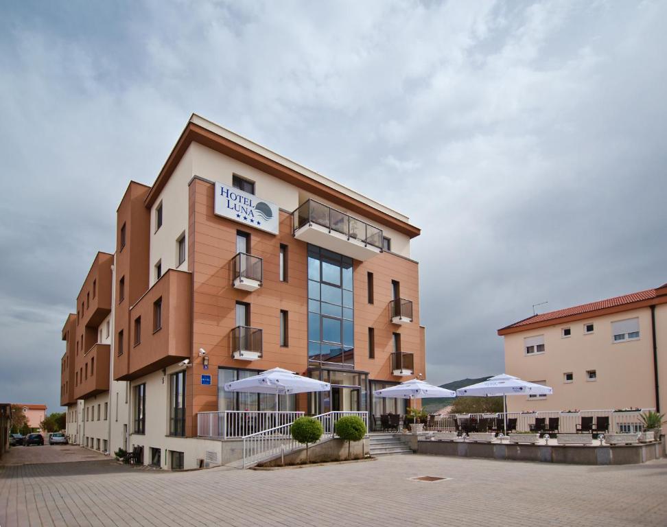 un hotel con sombrillas frente a un edificio en Hotel Luna, en Međugorje