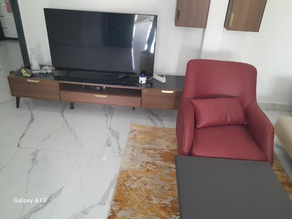 un soggiorno con sedia rossa e TV di Nkc guest a Nouakchott