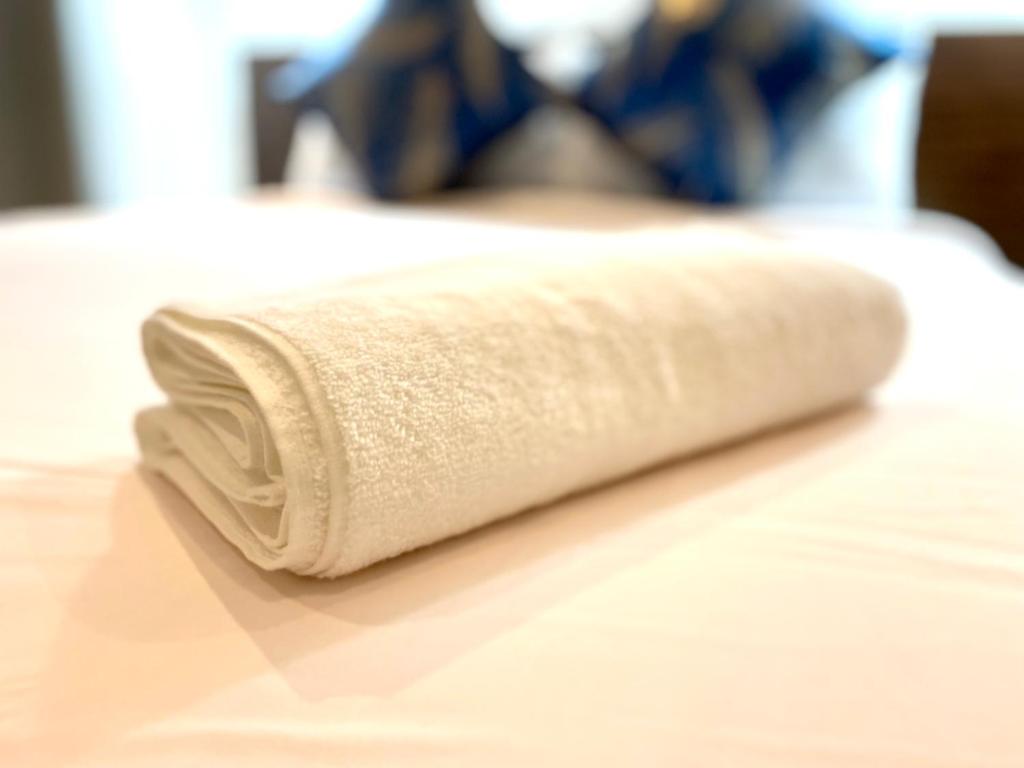 een witte handdoek bovenop een bed bij KS Spacious Studio Apartment in Accra