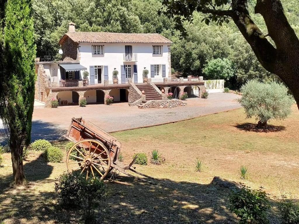 une grande maison blanche avec une charrette en bois devant elle dans l'établissement Mas La Solarie au coeur des Cévennes avec accès privé à la rivière, à Thoiras