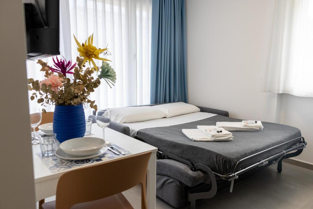 a small room with a bed and a table with flowers at Amarena Vacanze in Porto Recanati