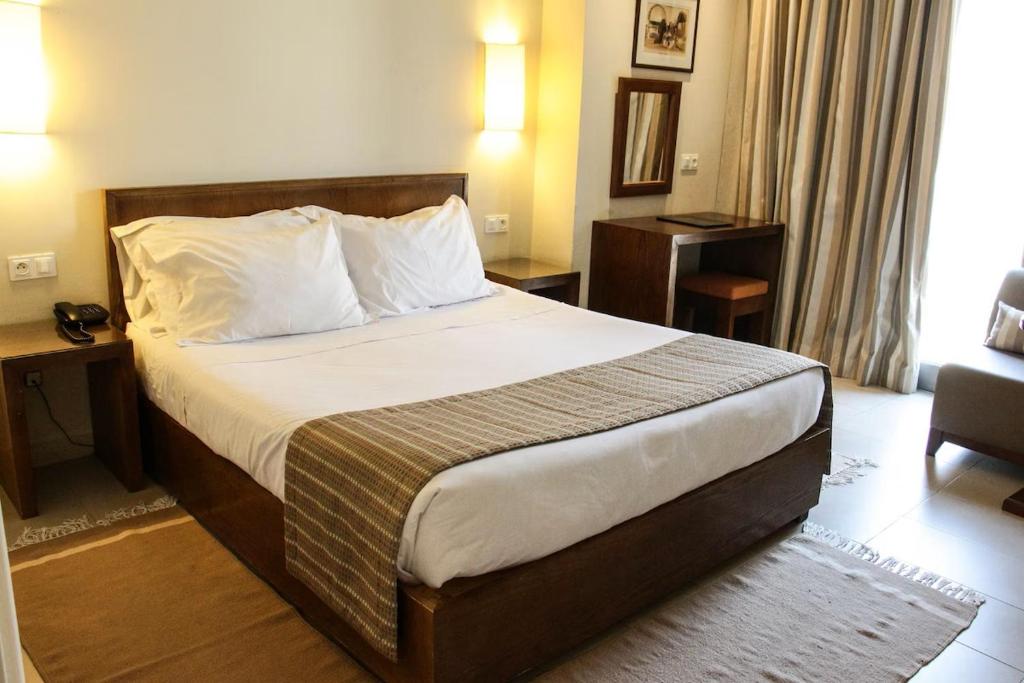 a hotel room with a bed and a chair at Hôtel Résidence Le Consul in Tunis