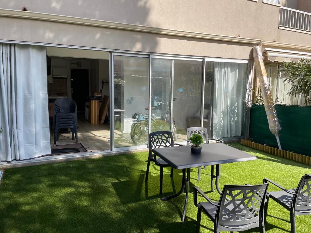 un patio avec une table et des chaises sur l'herbe dans l'établissement Rez-de-jardin cap d agde résidence eurêka, au Cap d'Agde