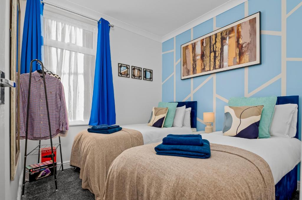 クリーソープスにあるCharming Apartment by the Seaの青い壁の部屋にベッドが2つある