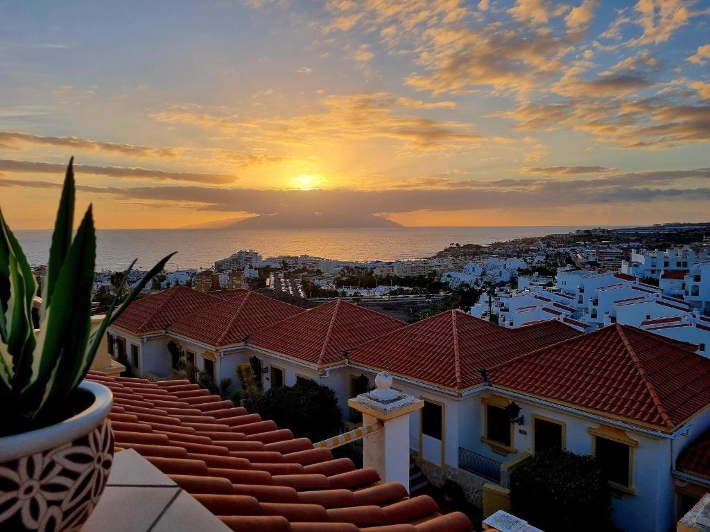 a sunset over the roofs of white buildings at Ocean view apartment with pools in Adeje