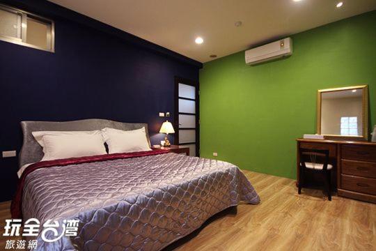 a bedroom with a bed and a green wall at Good Time B&amp;B in Jiufen