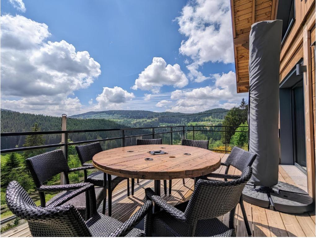 une table et des chaises en bois sur une terrasse avec vue dans l'établissement Chalet l'URSUS - séjour premium avec vue montagne, à Gérardmer