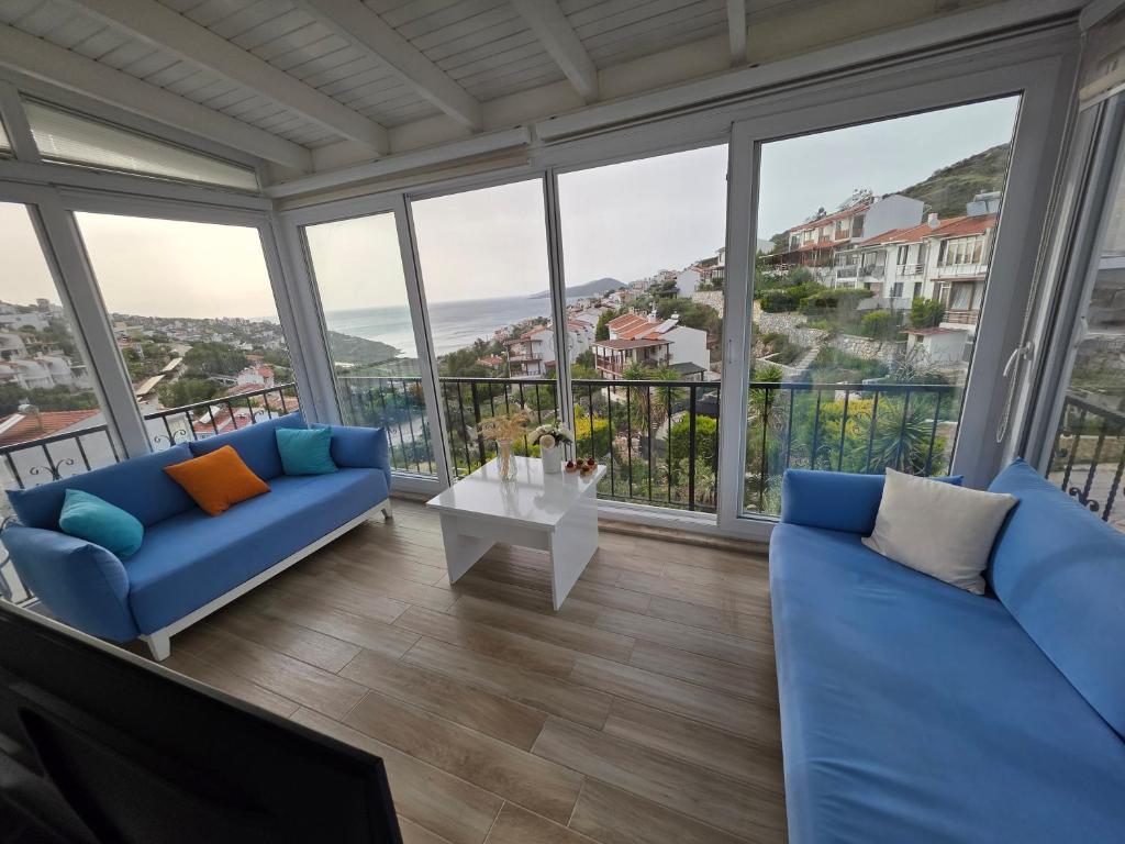a living room with blue furniture and large windows at Sevinc Akasya House in Milas